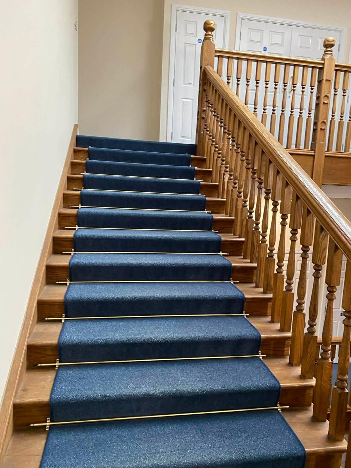 Navy stair runner held by brass stair rods over polished timber treads in Epsom