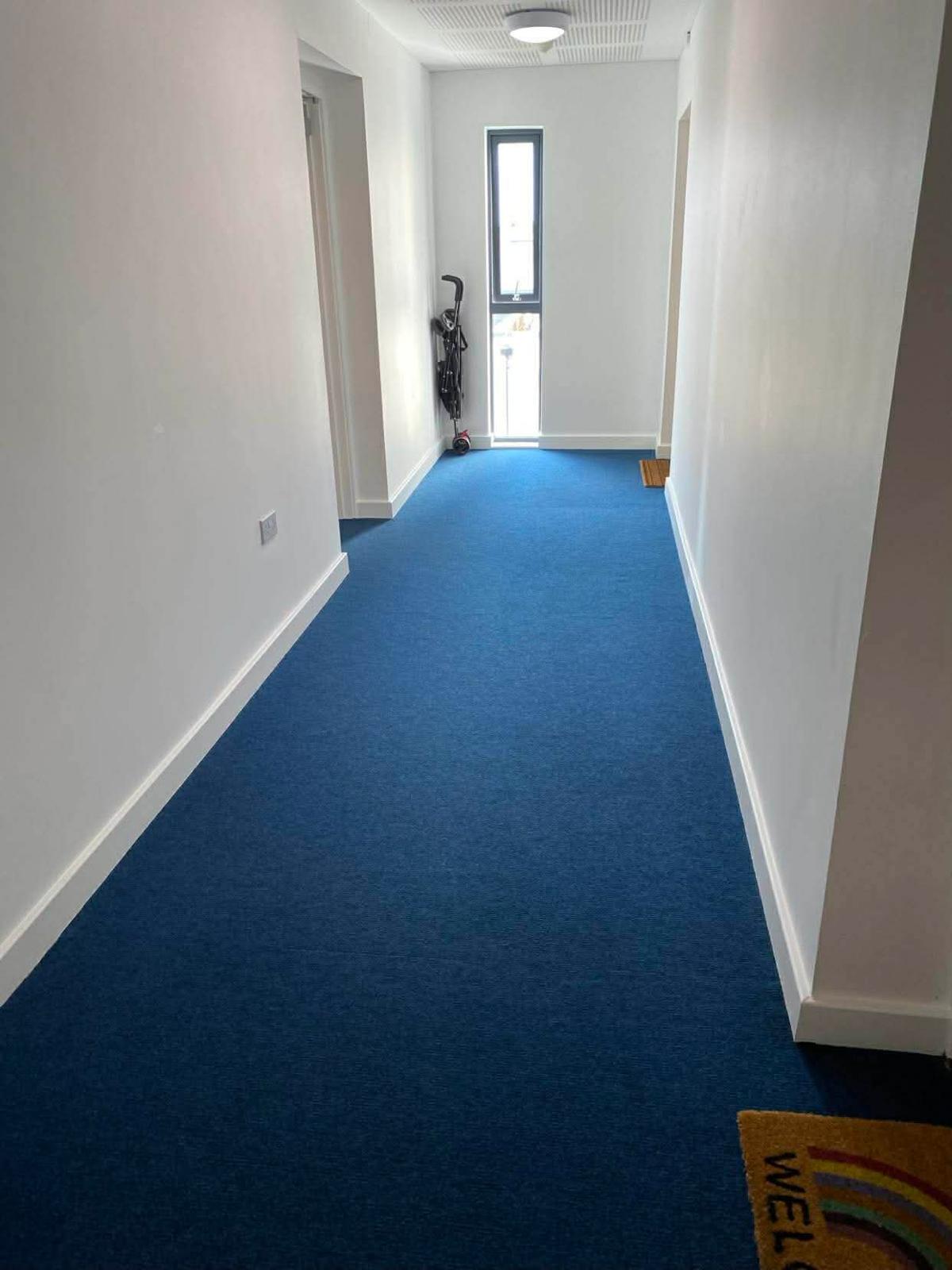 Blue carpeted corridor in the Kingston block leading to a window at the far end