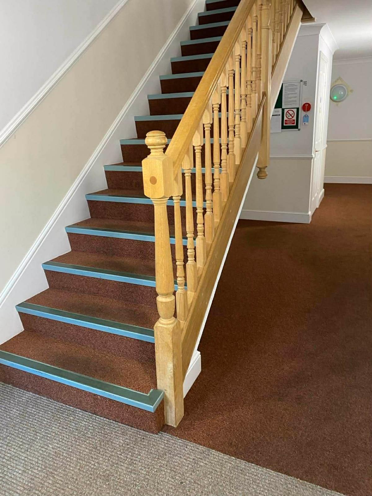 Foot of the Sutton communal staircase beside the fire notice board and entrance matting