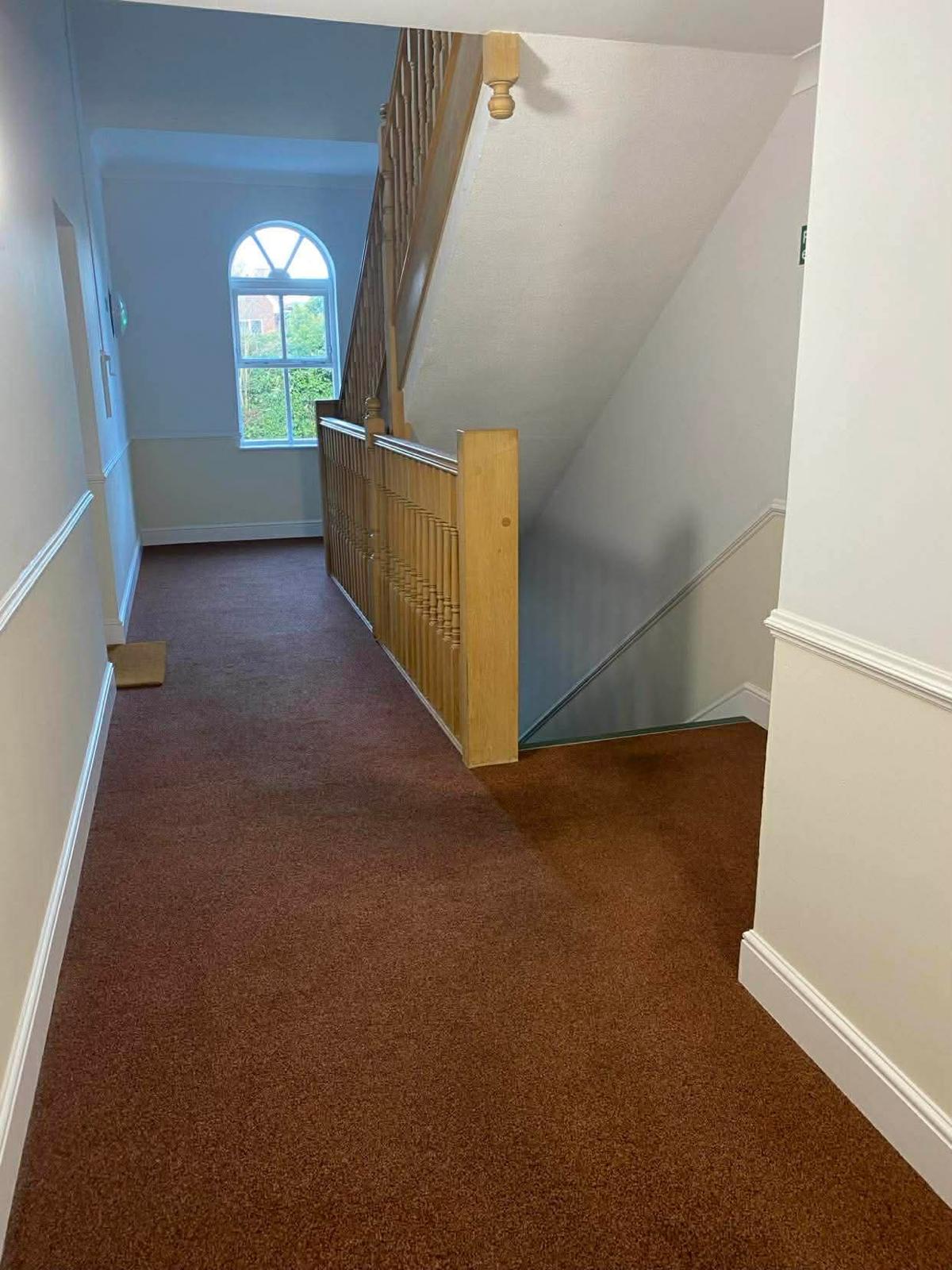 Upper landing in the Sutton block with an arched window above the carpeted floor