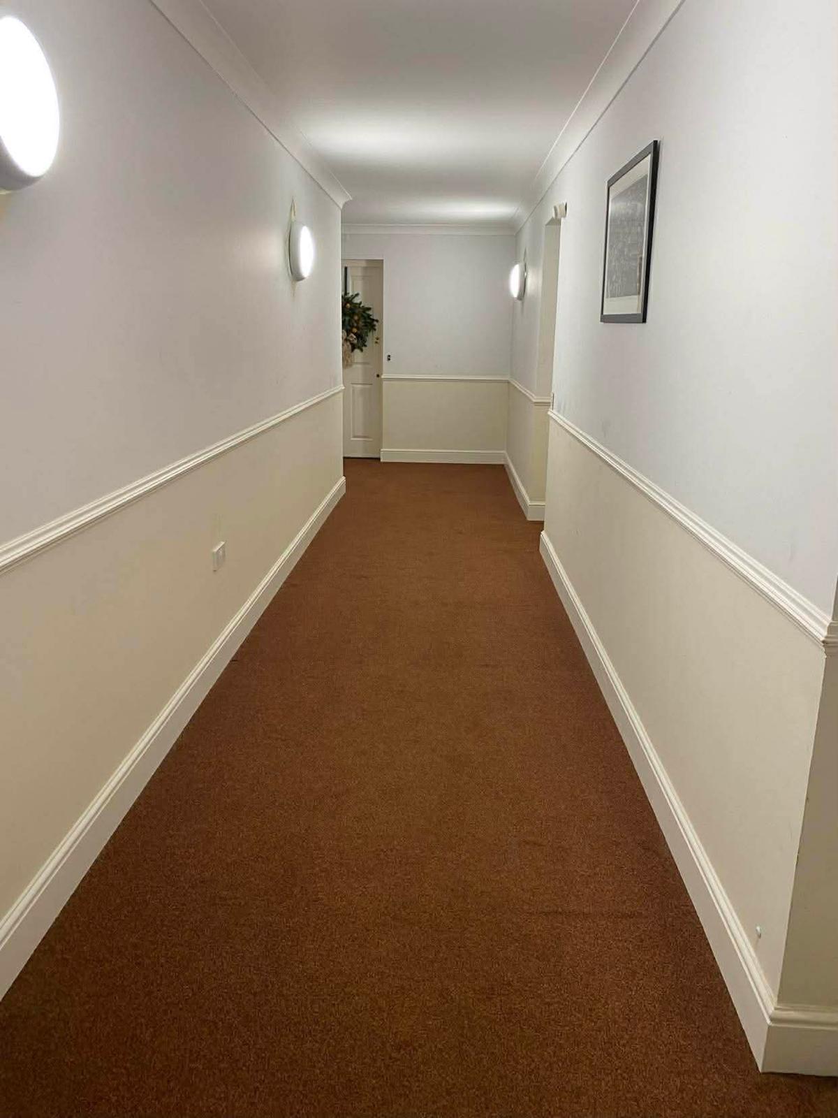 Long carpeted communal corridor in the Sutton block lit by wall lights