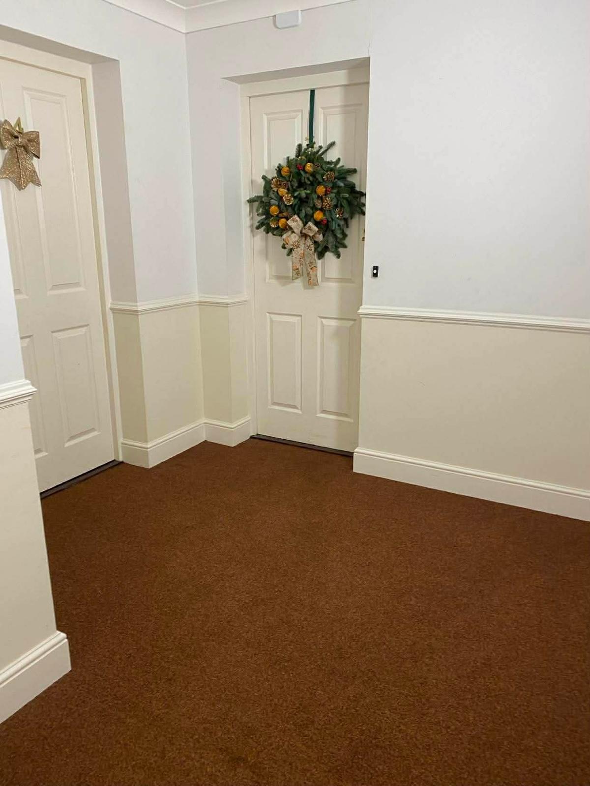 Landing outside two flat doors in the Sutton block, one with a resident's wreath