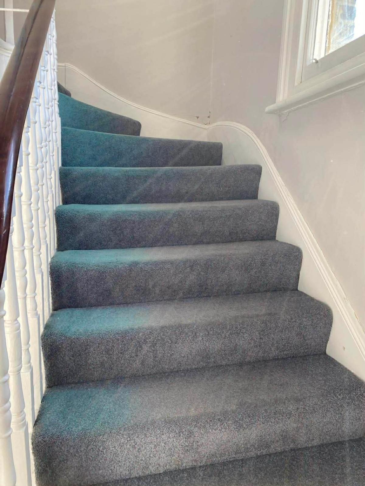 Grey carpeted stair with white spindles and a mahogany handrail in the first Wallington block