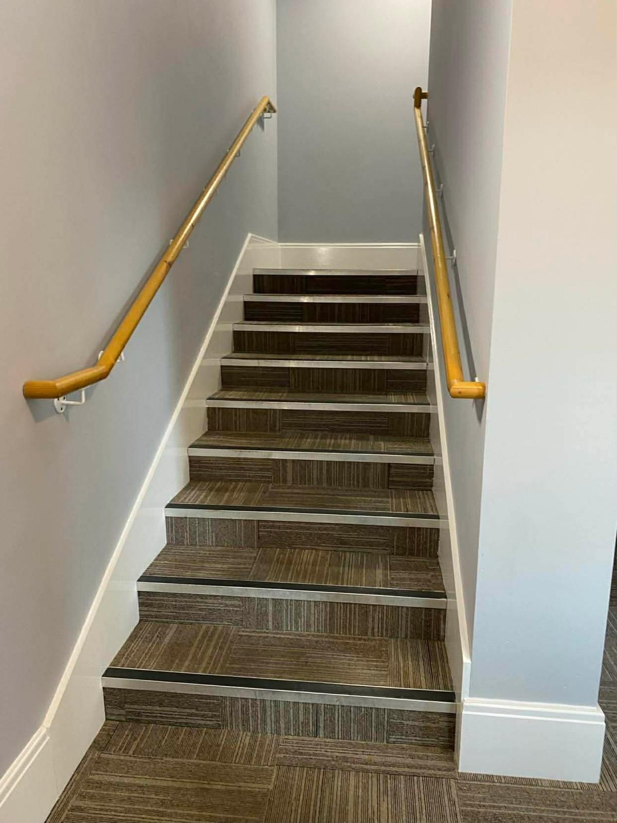 Carpet-tiled staircase with metal nosings and timber handrails in the second Wallington block