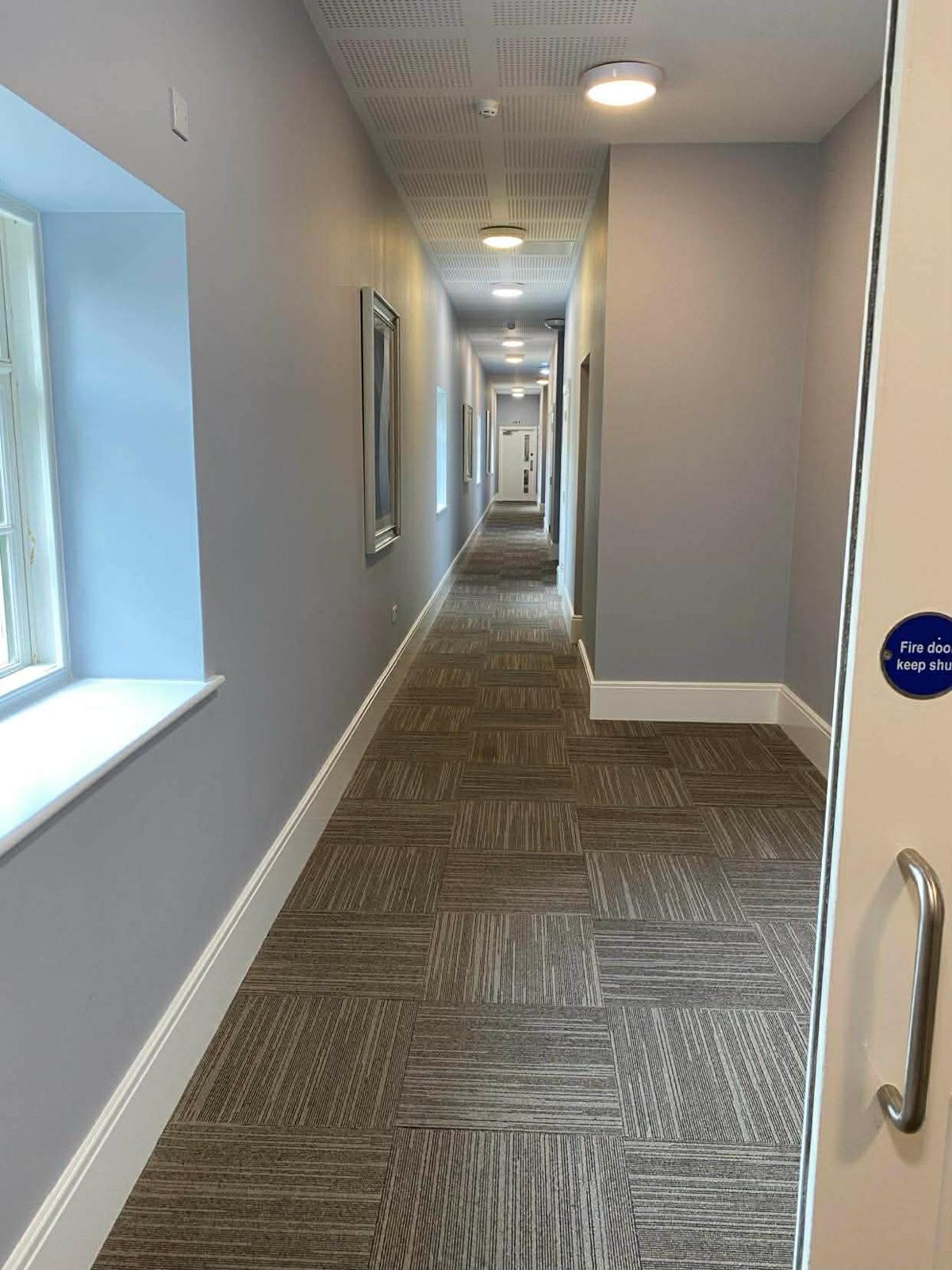 Long carpet-tiled corridor with fire doors in the second Wallington block