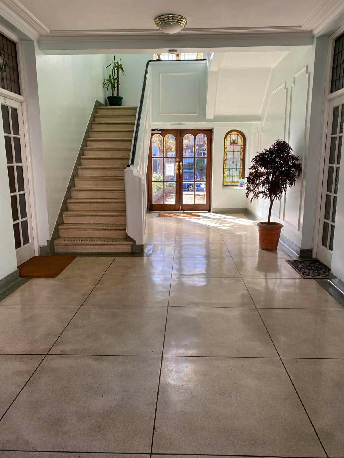 Tiled entrance hall in the Wimbledon development with a stone staircase and stained glass window