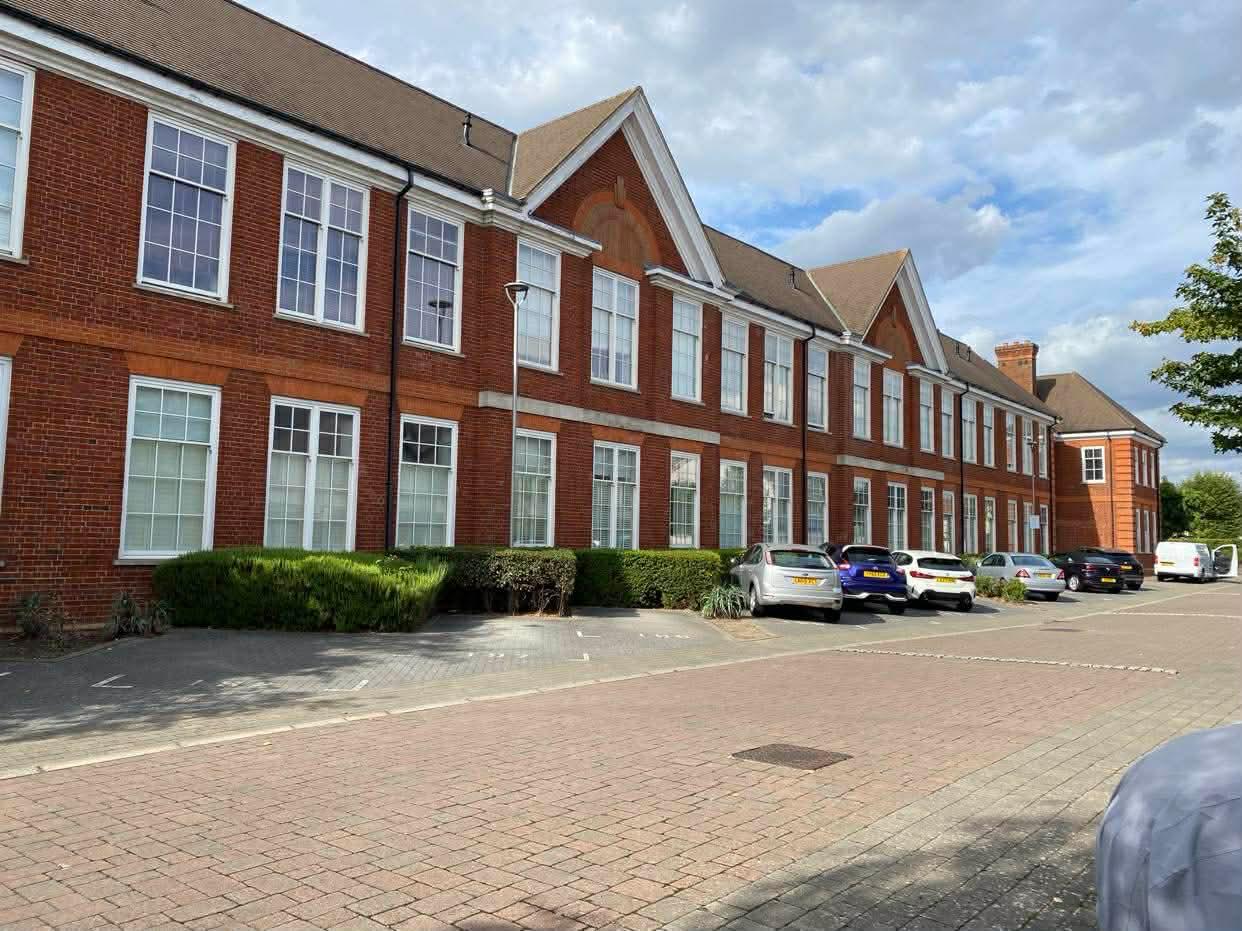 Long red brick frontage of the Wimbledon development seen along the parking area